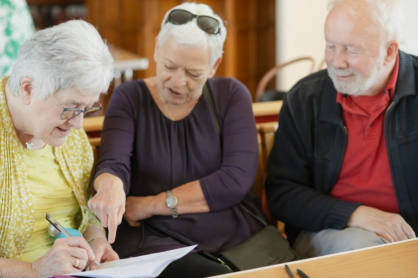 Three adults reviewing a printed document together at a table