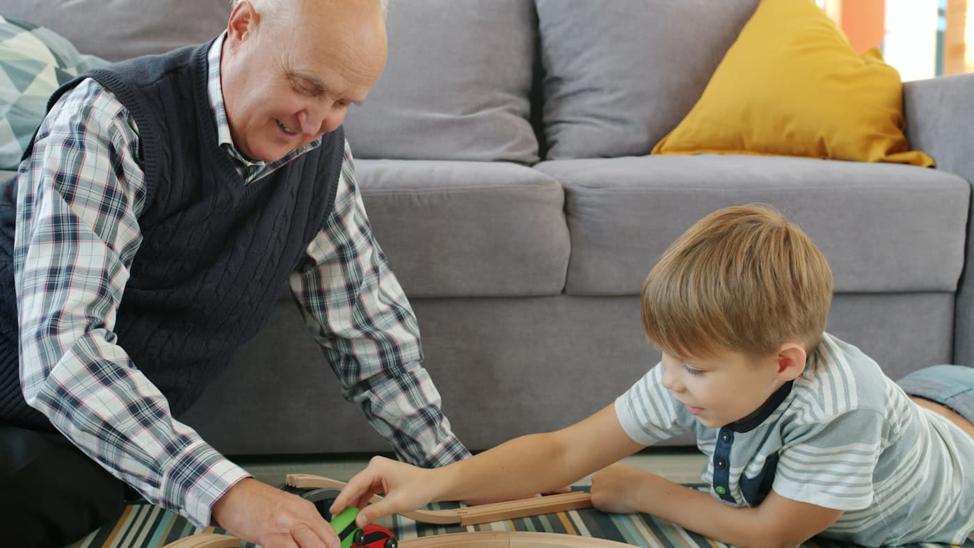 Grandfather and grandson playing together on a living room floor